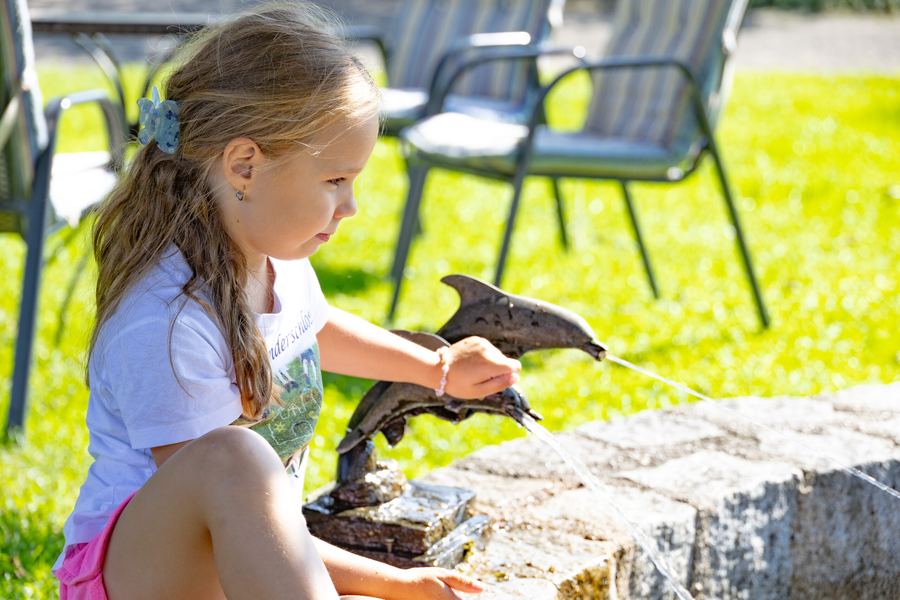 Mädchen spielt am Brunnen im Garten